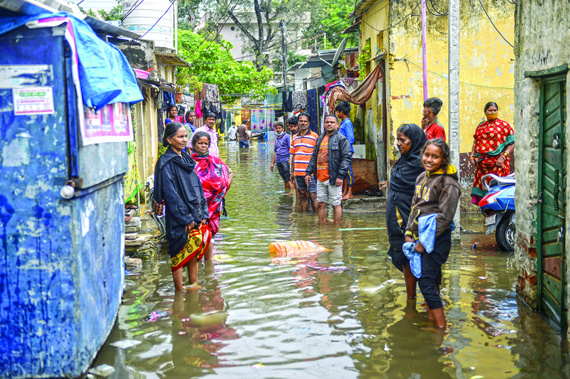 Residents gather on a flooded street outside their homes following heavy rains in Hyderabad on October 14, 2020. (Photo by NOAH SEELAM / AFP)