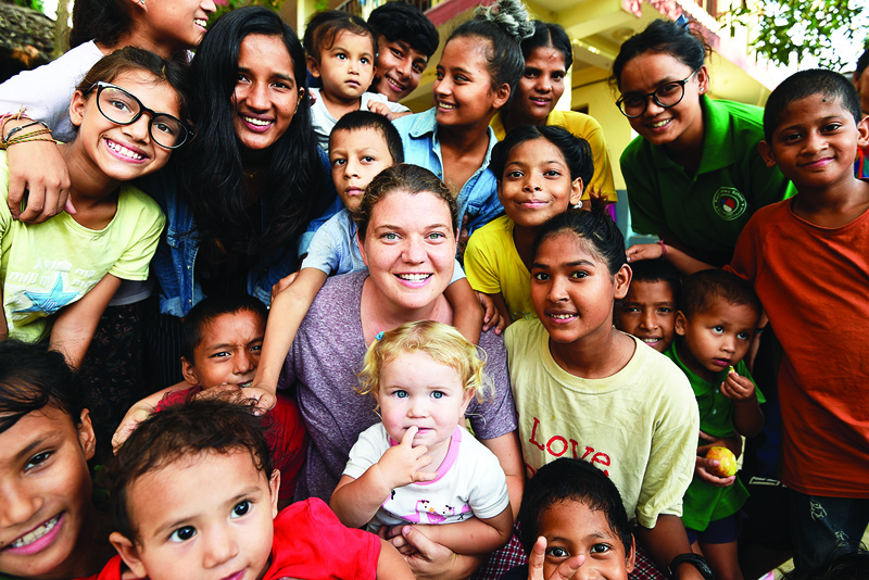 In this photograph taken on September 10, 2019, American philanthropist Maggie Doyne (C) poses for pictures along with children from the Kopila Valley Children's Home, at Surkhet District, some 600 km west of Kathmandu. - Kopila Valley Children's Home in west Nepal's Surkhet, founded by Doyne in 2008, now shelters 54 children. Her school is attended by 450 students who would otherwise have little chance at getting an education. (Photo by PRAKASH MATHEMA / AFP) / TO GO WITH Nepal-US-women-charity-education,INTERVIEW by Paavan MATHEMA