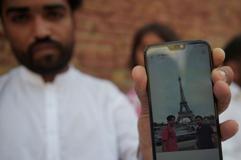 In this picture taken on September 29, 2020, Ghulam Mustafa, brother of Hassan Arshad (R in mobile picture), an 18-year-old Pakistani born who injured two people in a meat cleaver attack in Paris, shows a picture on a mobile phone of his brother in front of the Eiffel Tower, at his home in Kothli Qazi village some 130 kms from Islamabad. - Pakistani farmer Arshad Mehmood has been filled with pride since his son stabbed two people outside the former offices of satirical magazine Charlie Hebdo in Paris last week, in the latest attack to expose the violent consequences of blasphemy allegations. Zaheer Hassan Mehmood, who was born in Pakistan, has confessed to the attack, saying he was motivated by the magazine's recent republication of cartoons of the Prophet Mohammed, which are proscribed in Islam. (Photo by Farooq NAEEM / AFP)