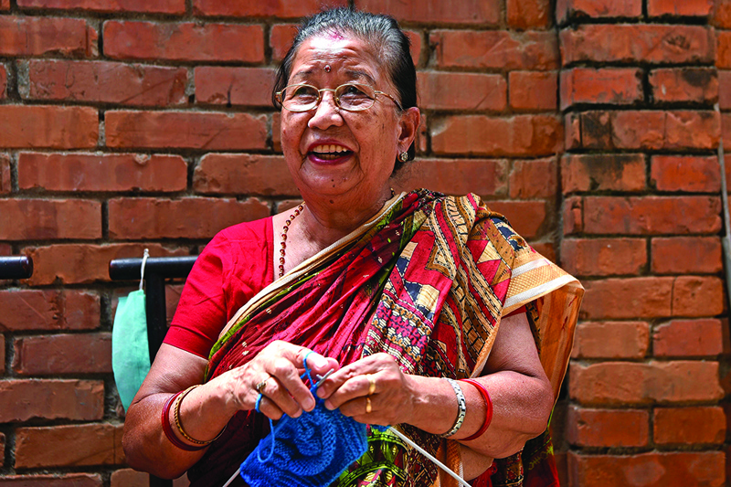 In this picture taken on August 6, 2020, Champa Devi Tuladhar knits during an interview with AFP in Kathmandu. - Every winter, Lorina Sthapit and her cousins would warm their feet in woollen socks freshly knitted by their grandmother. As the brightly coloured pairs stacked up in her cupboard, the 31-year-old felt inspired to share the bundles of love with the world -- co-founding a crafts venture that not only sells such handmade products but also delves into the seldom-told lives of its mostly elderly female creators. (Photo by PRAKASH MATHEMA / AFP) / To go with AFP story  Nepal-gender-arts-lifestyle-elderly, INTERVIEW by Paavan MATHEMA