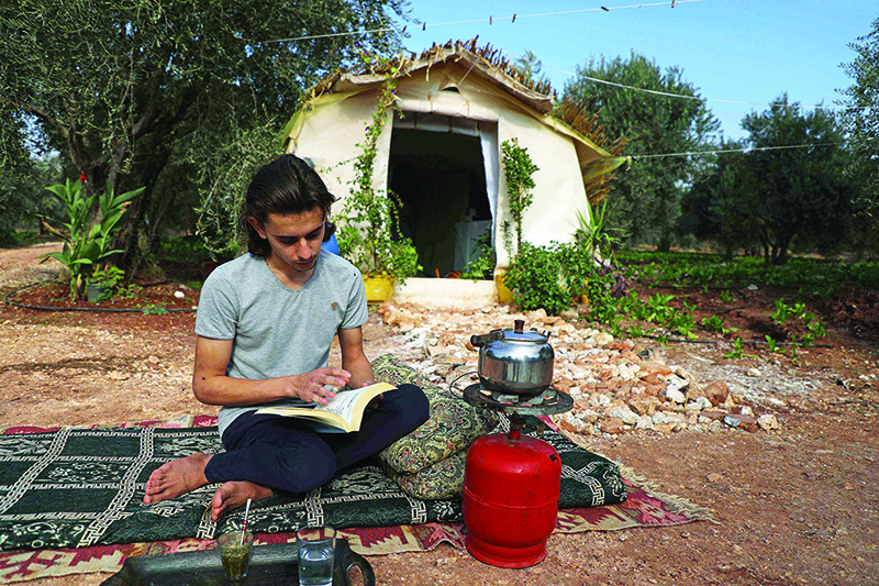 Wissam Diab reads a book sited in front of his new home.