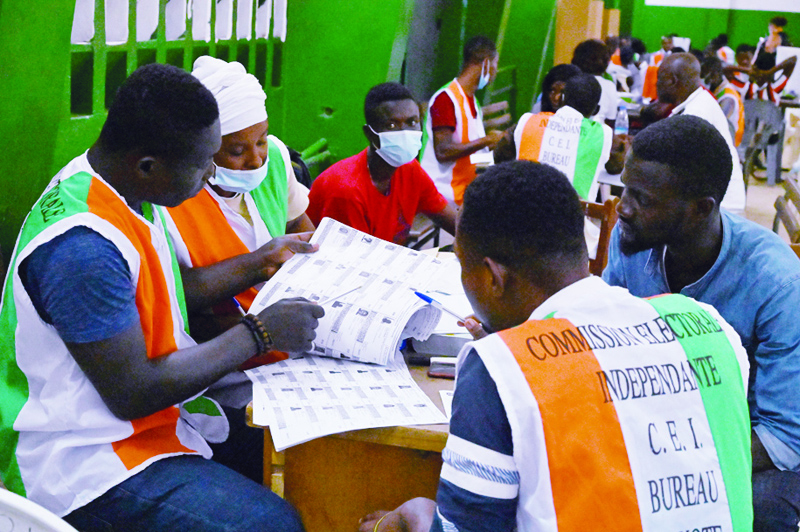 Electoral commission officials check the voter's roll as they count votes at a polling station in Abidjan on October 31, 2020, after Ivory Coast's presidential election. (Photo by Issouf SANOGO / AFP)