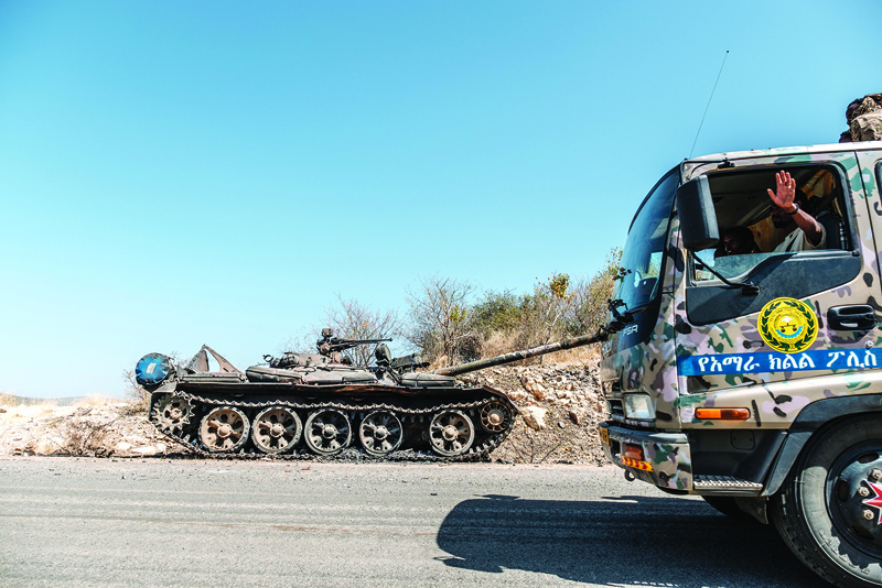 A damaged tank stands abandoned on a road as a truck of the Amhara Special Forces passes by near Humera, Ethiopia, on November 22, 2020. - Prime Minister Abiy Ahmed, last year's Nobel Peace Prize winner, announced military operations in Tigray on November 4, 2020, saying they came in response to attacks on federal army camps by the party, the Tigray People's Liberation Front (TPLF). nHundreds have died in nearly three weeks of hostilities that analysts worry could draw in the broader Horn of Africa region, though Abiy has kept a lid on the details, cutting phone and internet connections in Tigray and restricting reporting. (Photo by EDUARDO SOTERAS / AFP)
