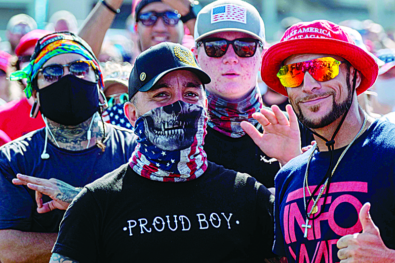 TOPSHOT - Supporters wearing Proud Boy clothing wave to the camera during a Make America Great Again campaign rally in Tampa, Florida on October 29, 2020. (Photo by Ricardo ARDUENGO / AFP)