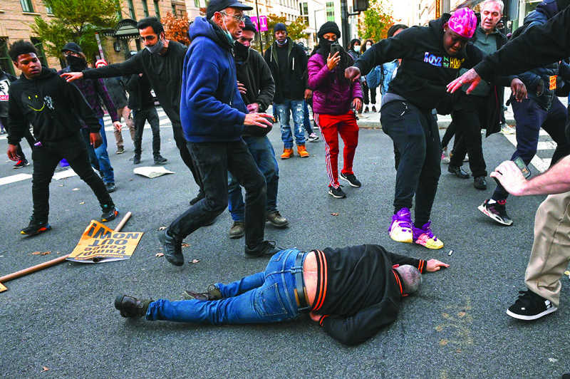 A supporter of US President Donald Trump lying on the floor is kicked as he is attacked by anti-Trump demonstrators in Black Lives Matter Plaza in Washington, DC on November 14, 2020. (Photo by Roberto SCHMIDT / AFP)