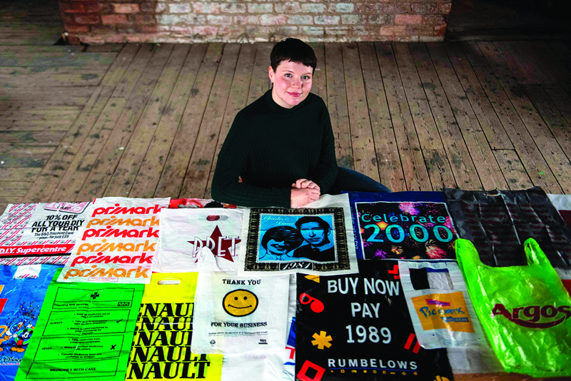 British artist Katrina Cobain, 24, poses for photographs with some of her collection of plastic bags from which she intends to start The Plastic Bag Museum in Glasgow on October 28, 2020. - Katrina Cobain unwraps a parcel and removes its precious contents, slowly and delicately as if she were handling an ancient scroll of papyrus. But the items she places on the table of a makeshift studio in an old tobacco pipe factory in the east end of Glasgow are rather more mundane -- plastic carrier bags. For Cobain, 24, every plastic bag tells a story of the modern age and so, two years ago, she became a collector and plans to start a museum. (Photo by ANDY BUCHANAN / AFP) / TO GO WITH AFP STORY BY STUART GRAHAM