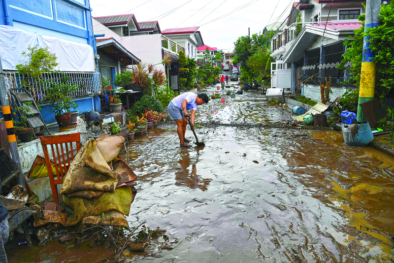 TOPSHOT - A resident shovels mud from a neighbourhood street following flooding in Batangas City on November 2, 2020, after super Typhoon Goni made landfall in the Philippines on November 1. (Photo by TED ALJIBE / AFP)