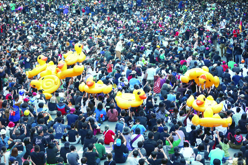 Large inflatable ducks are passed around the crowd as pro-democracy protesters gather for an anti-government rally at a major intersection in Bangkok on November 18, 2020. (Photo by Jack TAYLOR / AFP)