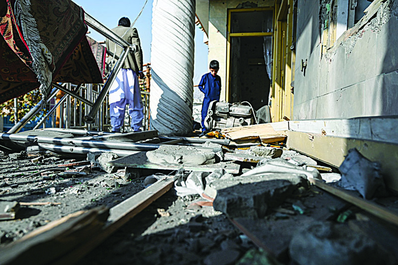 People inspect a damaged house after several rockets land at Khair Khana, north west of Kabul on November 21, 2020. - A series of loud explosions shook central Kabul on November 21, including several rockets that landed near the heavily fortified Green Zone where many embassies and international firms are based, officials said. (Photo by WAKIL KOHSAR / AFP)