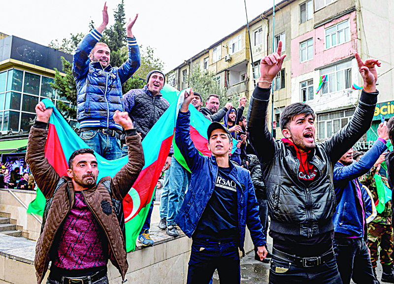 People hold Azeri flag as they celebrate the capture the town of Shusha in Baku on November 8, 2020, during the ongoing military conflict between Armenia and Azerbaijan over the breakaway region of Nagorno-Karabakh. - Azerbaijani President said on November 8 that his country's forces had captured the town of Shusha in Nagorno-Karabakh, in what would be a major strategic victory over the region's Armenian separatists. (Photo by Tofik BABAYEV / AFP)