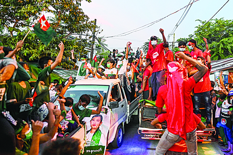 Supporters of the National League for Democracy (NLD) party (R) on a motorcade pass supporters of the opposition Union Solidarity and Development Party (USDP), during an election campaign event on the outskirts of Yangon on November 6, 2020, ahead of the November 8 general election. (Photo by Ye Aung THU / AFP)