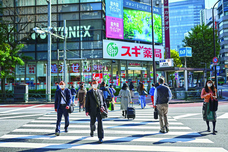 People walk on a pedestrian crossing in Tokyo on November 16, 2020, as government data showed Japan's economy exited recession in the third quarter, growing a better-than-expected 5.0 percent following a record contraction. (Photo by Charly TRIBALLEAU / AFP)