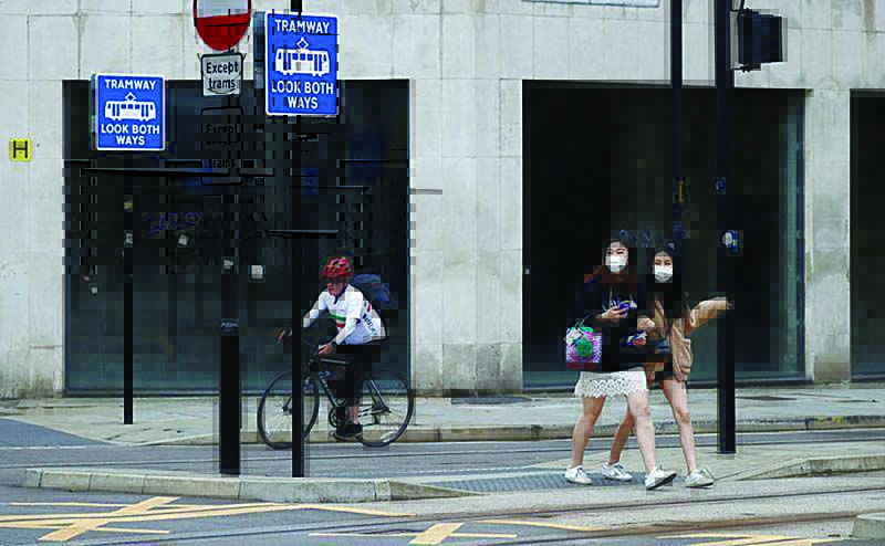 FILE PHOTO: People wearing protective face coverings walk past an empty retail unit following the outbreak of the coronavirus disease (COVID-19), in Manchester, Britain, July 8, 2020. REUTERS/Phil Noble