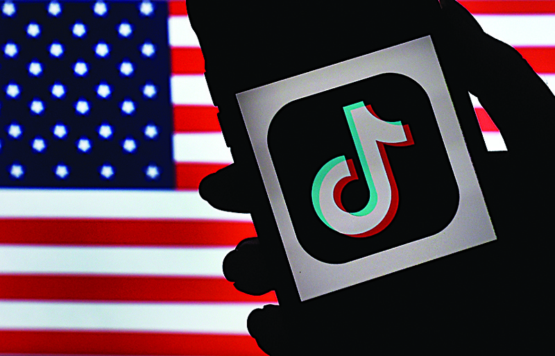 (FILES) In this file photo illustration taken on August 03, 2020, the social media application logo, TikTok is displayed on the screen of an iPhone on an American flag background in Arlington, Virginia. - US authorities have given the Chinese owner of TikTok two more weeks to sell the social media sensation in order to resolve national security concerns voiced by the Trump administration, according to a court filing on November 13, 2020. (Photo by Olivier DOULIERY / AFP)