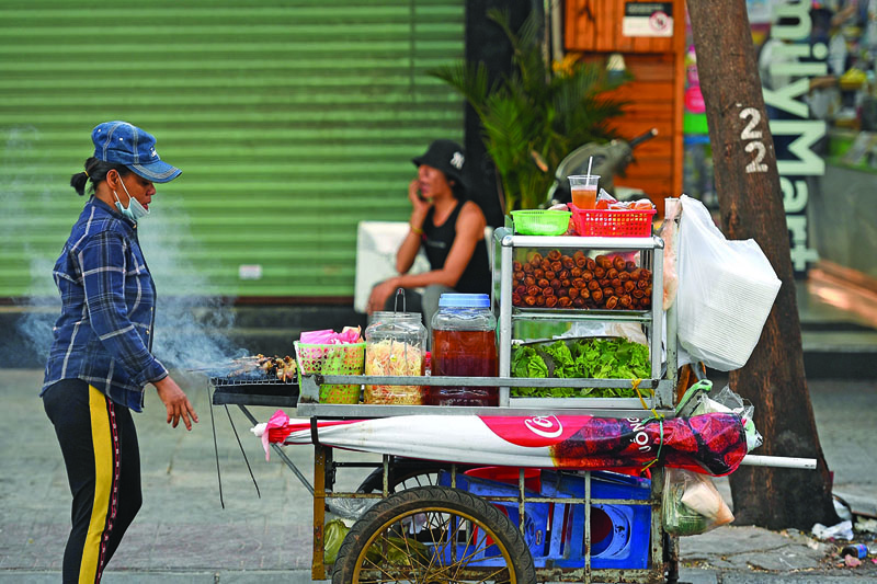 This photograph taken on September 8, 2020 shows a street food vendor selling spring rolls and grilled pork in Ho Chi Minh city. - Vietnam's fragrant noodle soups and fresh spring rolls have won fans across the globe, but mounting food safety scandals on the country's streets are sparking a rising tide of anxiety among millenials about what they eat. (Photo by Nhac NGUYEN / AFP) / To go with Vietnam-food-health-economy, FEATURE by Alice PHILIPSON and TRAN Thi Minh Ha
