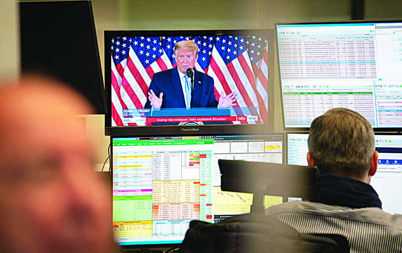 US President Donald Trump is displayed on a television screen as traders work at the stock exchange in Frankfurt am Main, western Germany, on November 4, 2020. - Volatility gripped financial markets with the US election outcome clouded by huge uncertainty. European stock markets, which opened sharply lower after US President Donald Trump said he would go to the Supreme Court to dispute the US vote count, turned higher in late morning deals. (Photo by Frank Rumpenhorst / dpa / AFP) / Germany OUT
