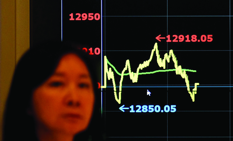 A woman walks past a monitor showing the stocksí index outside the Taiwan Stocks Exchange in Taipei on November 5, 2020. (Photo by Sam Yeh / AFP)