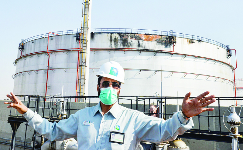 An employee at the Saudi Aramco oil facility, mask-clad due to the COVID-19 coronavirus pandemic, gestures while standing near a damaged silo, at the plant in Saudi Arabia's Red Sea city of Jeddah on November 24, 2020. - Yemen's Huthi rebels launched a missile attack on the facility on November 23, triggering an explosion and a fire in a fuel tank, officials said. The strike occurred the day after the kingdom hosted a virtual summit of G20 nations, and more than a year after the targeting of major Aramco sites that caused turmoil on global oil markets. (Photo by FAYEZ NURELDINE / AFP)