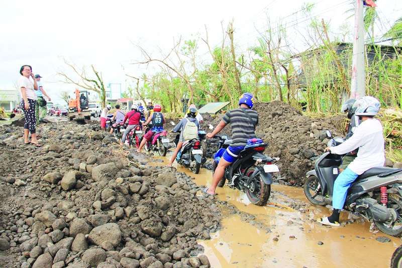 Motorists make their way through boulders washed from nearby Mayon volcano along a damaged road  after super Typhoon Goni hit the town of Malilipot, Albay province, south of Manila on November 1, 2020. - At least seven people were killed as Typhoon Goni pounded the Philippines on November 1, ripping off roofs, toppling power lines and causing flooding in the hardest-hit areas where hundreds of thousands have fled their homes. (Photo by Charism SAYAT / AFP)