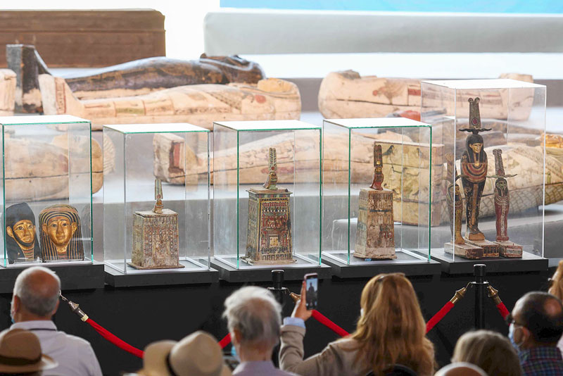 A picture shows statues and funerary masks on display during the unveiling of an ancient treasure trove of more than a 100 intact sarcophagi, at the Saqqara necropolis 30 kms south of the Egyptian capital Cairo, on November 14, 2020. - Egypt announced the discovery of an ancient treasure trove of more than a 100 intact sarcophagi, the largest such find this year. The sealed wooden coffins, unveiled on site amid fanfare, belonged to top officials of the Late Period and the Ptolemaic period of ancient Egypt. They were found in three burial shafts at depths of 12 metres (40 feet) in the sweeping Saqqara necropolis south of Cairo. (Photo by Ahmed HASAN / AFP)