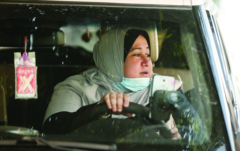 The first female Palestinian taxi driver in the Gaza Strip, Nayla Abu Jubbah, 39, sits at her vehicle as she works in Gaza City on November 17, 2020. - Jubbah launched a small revolution this week by becoming the first female taxi driver in the deeply conservative Gaza Strip. In the coastal Palestinian territory women have the same legal rights as men to drive a vehicle, but in practice the trade of taxi driver has been exclusively male -- until now (Photo by MAHMUD HAMS / AFP)
