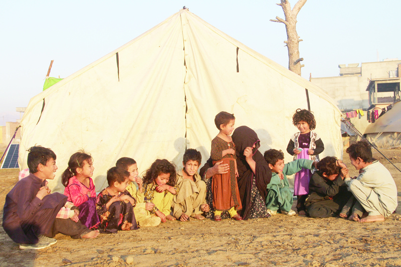 Internally displaced children sit outside a tent at a refugee camp in Khost province on November 17, 2020. (Photo by FARID ZAHIR / AFP)