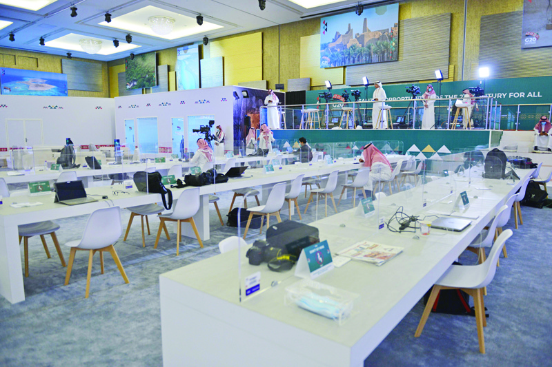 Journalists work in an almost empty media room setup for the coverage of the G20 summit,  held virtually due to the COVID-19 coronavirus pandemic, in the Saudi capital Riyadh, on November 20, 2020. - Mask-clad reporters filed into a Riyadh ballroom-turned-media centre after mandatory temporary checks, to cover physically a virtual G20 summit originally conceived as a grand coming-out party for host Saudi Arabia. (Photo by FAYEZ NURELDINE / AFP)