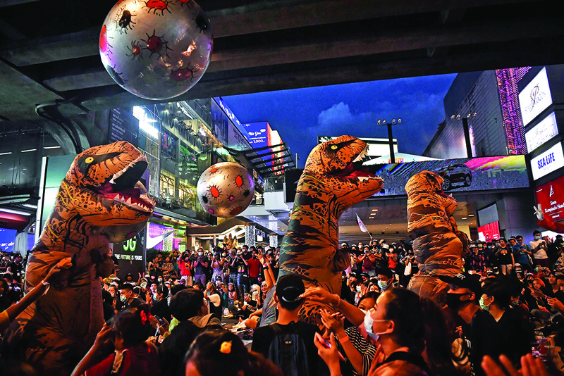 Protesters dressed in dinosaur costumes play with inflatable balls representing asteroids -- the impact from which contributed to the extinction of the dinosaurs, which activists said represents the older generation of Thai politicians -- during a 'Bad Student' rally in Bangkok on November 21, 2020. (Photo by Lillian SUWANRUMPHA / AFP)