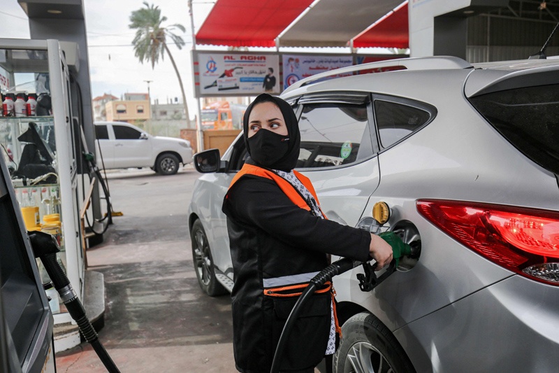 Salma al-Najjar, a 16-year-old Palestinian who works at a petrol station to help her family with income, refuels a car in Khan Yunis in southern Gaza Strip, 24 November 2020. (Photo by SAID KHATIB / AFP)