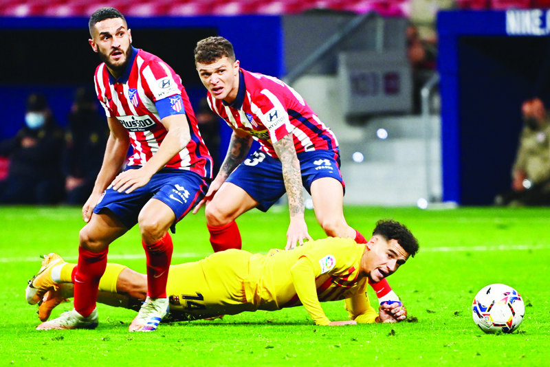 Barcelona's Brazilian midfielder Philippe Coutinho (bottom) falls after challenging Atletico Madrid's Spanish midfielder Koke (L) and Atletico Madrid's English defender Kieran Trippier during the Spanish League football match between Club Atletico de Madrid and FC Barcelona at the Wanda Metropolitano stadium in Madrid on November 21, 2020. (Photo by GABRIEL BOUYS / AFP)