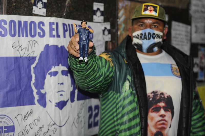 A supporter of Argentine former football star and coach of Gimnasia y Esgrima La Plata, Diego Maradona, holds a doll depicting him as he remains outside the private clinic where he underwent a brain surgery for a blood clot, in Olivos, Buenos Aires province, Argentina, on November 4, 2020. - Argentine football star Diego Maradona underwent successfully a brain surgery for a blood clot at a private clinic in Buenos Aires on Tuesday, his doctor said. (Photo by JAVIER GONZALEZ TOLEDO / AFP)