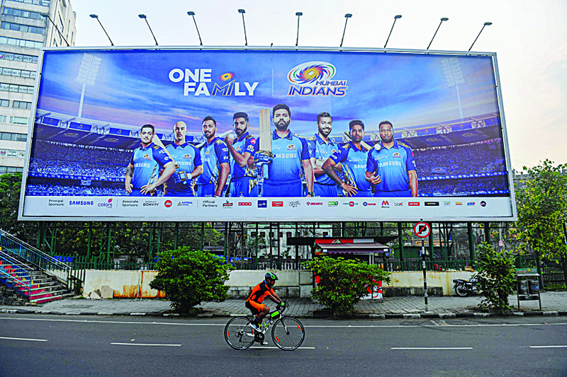In this picture taken on October 10, 2020, a cyclist rides past a hoarding of Mumbai Indians cricketers of the Indian Premier League (IPL) cricket tournament in Mumbai. - Unable to bet legally, tens of millions of Indian cricket fans have turned to fantasy games based on the Indian Premier League, which have exploited a loophole to create a billion-dollar industry. (Photo by Indranil MUKHERJEE / AFP) / To go with 'CRICKET-IND-IPL-FANTASY-INDIA', FOCUS by Vishal MANVE with Faisal KAMAL in Delhi