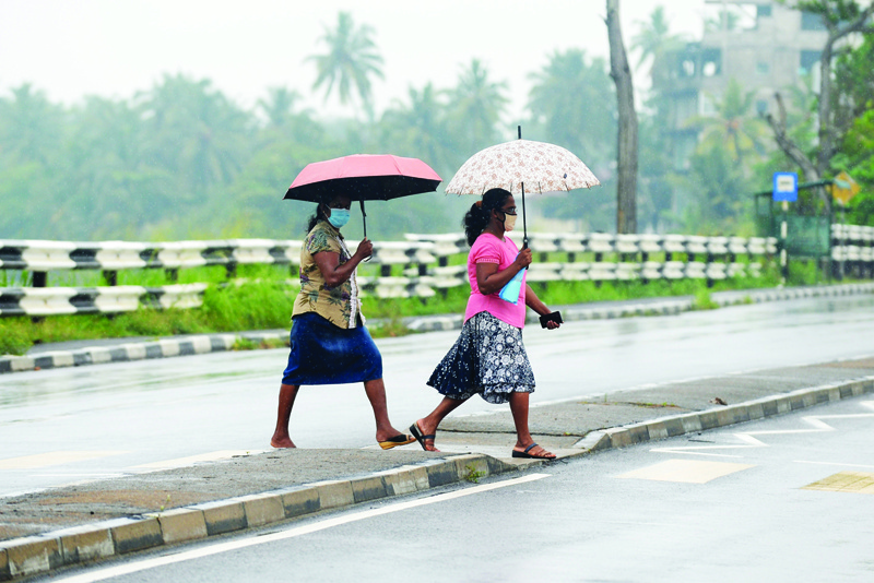 Women walk through a road during a rain shower as cyclone Nivar approaches, in Beruwala, some 58 kms from the Sri Lankan capital of Colombo on November 25, 2020. - The cyclone's centre was expected to pass some 175 kilometres northeast of Sri Lanka's northern tip early on November 25. (Photo by LAKRUWAN WANNIARACHCHI / AFP)