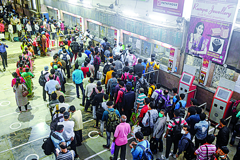 Passengers queue to buy tickets before boarding trains at a suburban railway station in Kolkata on November 11, 2020, as the local train services resume in West Bengal state. (Photo by Dibyangshu SARKAR / AFP)
