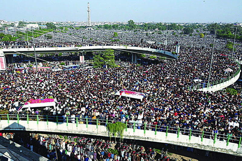 Activists and supporters of Tehreek-e-Labbaik Pakistan (TLP) gather around an ambulance (L) carrying the coffin of Khadim Hussain Rizvi, founder of TLP, during his funeral ceremony in Lahore on November 21, 2020. - Massive crowds of maskless mourners gathered in Lahore on November 21 for the funeral of hardline Pakistani cleric Khadim Hussain Rizvi, who for years terrorised the country's religious minorities, incited riots and advocated the destruction of European nations in the name of fighting blasphemy. (Photo by Arif ALI / AFP)