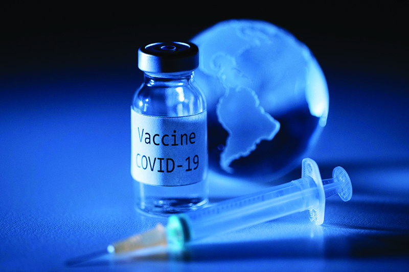 An illustration picture taken on November 19, 2020, shows a vial with Covid-19 Vaccine sticker, a syringe and an earth globe. (Photo by JOEL SAGET / AFP)