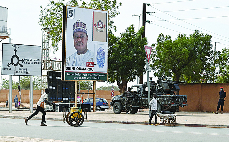 Nigerien Soldiers stand guard next to a campaign billboard of Niger presidential candidate for the National Movement for the Development of Society (MNSD), Seini Oumarou, in a street in Niamey, Niger, on December 22, 2020, ahead of the country's presidential elections scheduled for December 27, 2020. (Photo by Issouf SANOGO / AFP)