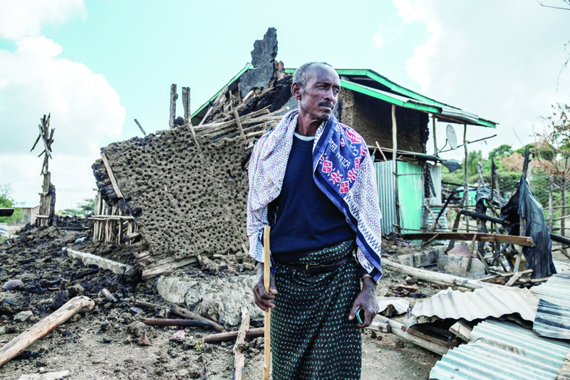 (FILES) In this file photo a man stands in front of his destroyed house in the village of Bisober in Ethiopia's Tigray region, on December 9, 2020. - The United Nations announced on December 17, 2020 a $35.6 million emergency aid package for civilians caught up in fighting in Ethiopia's Tigray region. Violence broke out in Tigray in early November when Ethiopian Prime Minister Abiy Ahmed launched military operations targeting Tigray's ruling party.nIn Ethiopia itself, $25 million will go toward the purchase of medicine and medical gear to help sick or (Photo by EDUARDO SOTERAS / AFP)