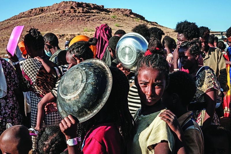 Ethiopian refugee children who fled the Ethiopia's Tigray conflict wait in a line for a food distribution by Muslim Aid at the Um Raquba refugee camp in Sudan's eastern Gedaref state on December 12, 2020. (Photo by Yasuyoshi CHIBA / AFP)