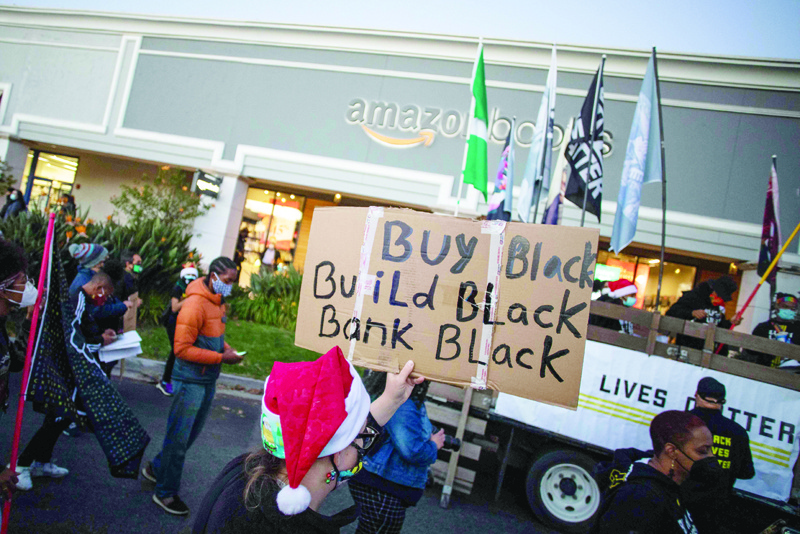 Protesters wearing Santa's hats hold signs as they demonstrate in front of the Amazon Book Store in the Waterside shopping center in the Marina Del Rey neighborhood of Los Angeles during a Black Lives Matter rally to demand social justice on December 19, 2020. - California accused Amazon of failing to adequately comply with subpoenas demanding details about coronavirus cases and protocols at its facilities here. Numerous front-line US employees at Amazon and Whole Foods have tested positive or are presumed positive for the coronavirus since March 2020. (Photo by Apu GOMES / AFP)