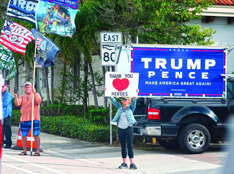 Supporters hold up signs as the motorcade with US President Donald Trump drives past in West Palm Beach, Florida on December 28, 2020. (Photo by ANDREW CABALLERO-REYNOLDS / AFP)