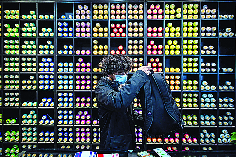 A graffiti artist, in a store where supplies are sold to make graffiti, prepares his bag with spray paint cans in Wuhan on November 22, 2020. (Photo by Hector RETAMAL / AFP)