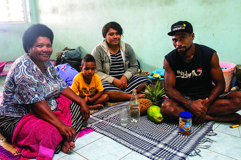 A Fijian family takes refuge in a temporary shelter from the strong damaging winds in the capital city of Suva on December 17, 2020. - Fijians were warned that no part of the Pacific island nation would escape the wrath of approaching super cyclone Yasa, expected to bring flash floods, huge waves and widespread destruction. (Photo by Leon LORD / AFP)