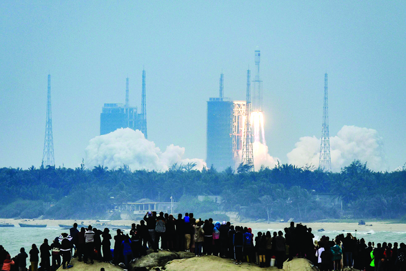 TOPSHOT - People watch a Long March-8 rocket, the latest China's Long March launch vehicle fleet, lifting off from the Wenchang Space Launch Center in southern China's Hainan province on December 22, 2020. (Photo by STR / AFP) / China OUT