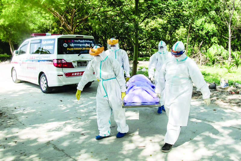 (FILES) In this file photo taken on November 25, 2020, volunteers wearing personal protective equipment (PPE) carry the body of a person suspected of dying from the Covid-19 coronavirus for their burial in the Hteinbin Muslim Cemetery in Yangon. - Living in a cemetery and isolated from his family, volunteer Sithu Aung lays another coronavirus victim to rest -- offering a crucial funeral rite to his Muslim community in Myanmar's virus-ravaged commercial capital. (Photo by Sai Aung Main / AFP) / TO GO WITH Myanmar-health-virus-religion-Islam by Lapyae KO