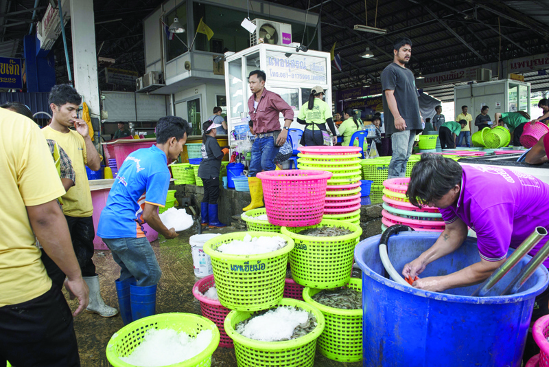 (FILES) In this file photo taken on September 20, 2018, Myanmar migrants and Thai workers gather fresh shrimps at a seafood market in the Thai coastal province of Samut Sakhon. - A Covid-19 coronavirus outbreak linked to a Thai seafood market in Samut Sakhon province surpassed 1000 cases on December 22, 2020, as authorities weigh up whether to introduce a wider lockdown. (Photo by Lillian SUWANRUMPHA / AFP)