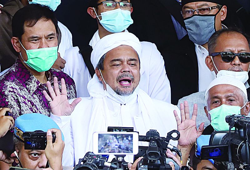 This picture taken on December 12, 2020 shows Indonesian Muslim cleric Rizieq Shihab (C) surrounded by his supporters upon arrival at the police headquarters in Jakarta, before he was arrested on December 13 over allegations of breaching coronavirus restrictions after holding a series of mass gatherings. (Photo by JENAYA / AFP)