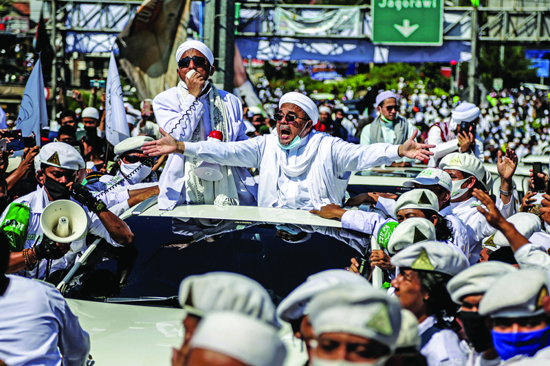 (FILES) In this file photo taken on November 13, 2020, Muslim cleric Rizieq Shihab (C), leader of the Indonesian hardline organisation FPI (Front Pembela Islam or Islamic Defenders Front), gestures to supporters as he arrives to inaugurate a mosque in Bogor. - Indonesia has banned an influential hardline Islamic group as police held its leader in custody over allegations he violated virus protocols by holding mass gatherings, the country's chief security minister said on December 30, 2020. (Photo by ADITYA SAPUTRA / AFP)