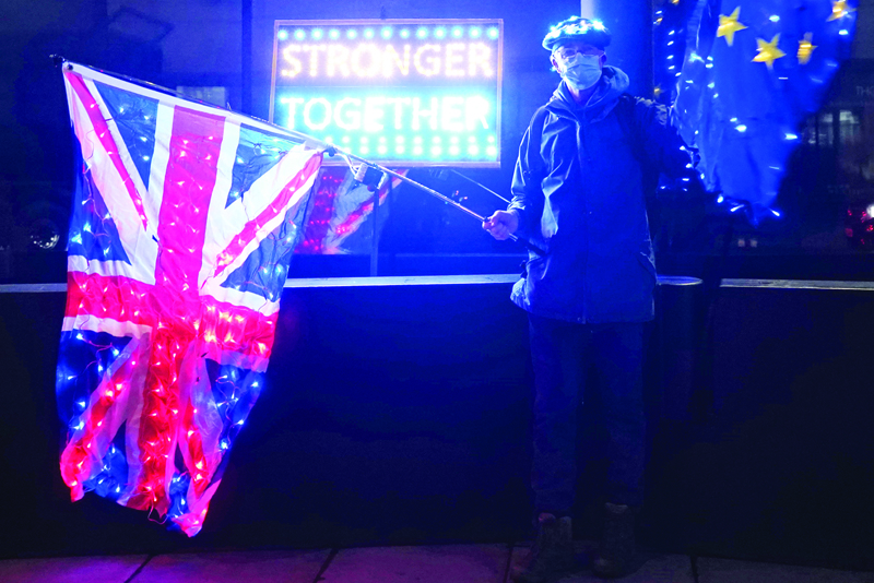 An anti-Brexit protester stands with Union and Eu flags outside a conference centre in central London on December 4, 2020, as talks continue on a trade deal between the EU and the UK. - With just a month until Britain's post-Brexit future begins and trade talks with the European Union still deadlocked, the UK government on Tuesday urged firms to prepare as it scrambles to finish essential infrastructure. (Photo by Niklas HALLE'N / AFP)