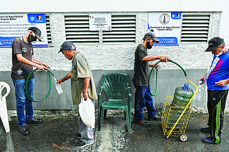 People fill plastic containers with water from a spring water tank at the Chacao neighborhood in Caracas on October 28, 2020, amid the new coronavirus pandemic. - The drilling of wells in the Venezuelan capital gained strength during the pandemic, in view of the deficient service of drinking water. (Photo by Federico PARRA / AFP)